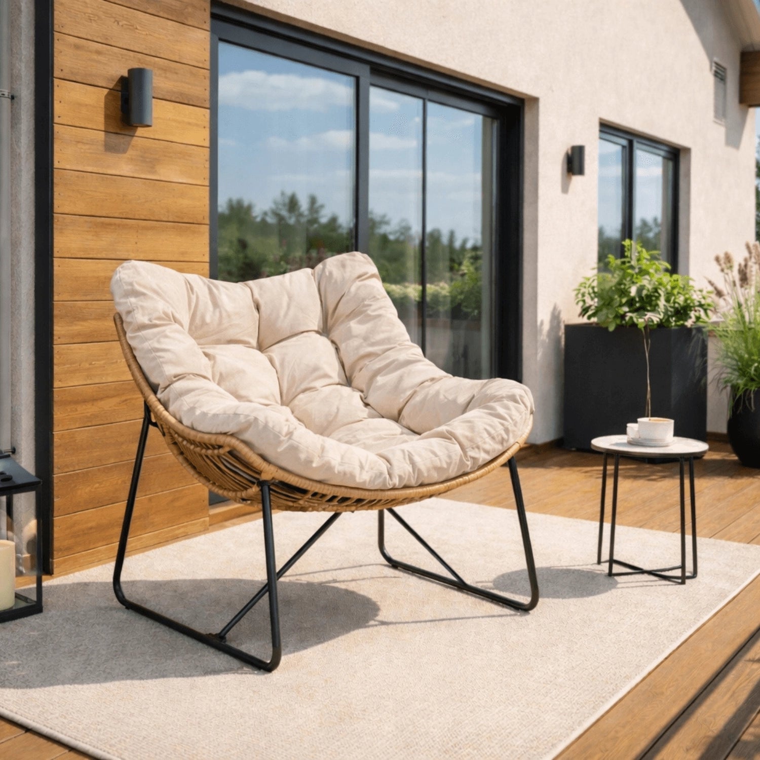 FIN Loungesessel in Beige mit Rattanoptik und schwarzem Metallgestell auf einer Terrasse
